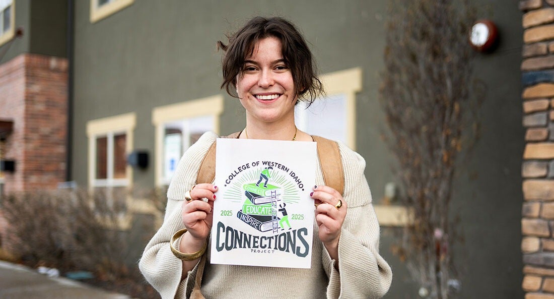 A picture of a student holding up a printed graphic logo.