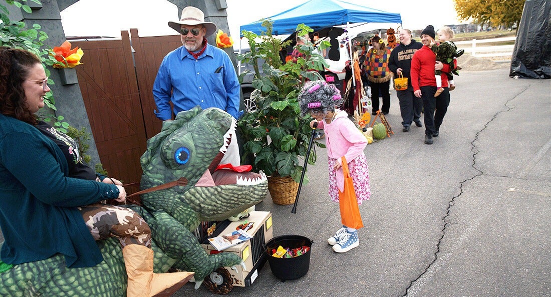 Children and adults in costumes enjoy a Halloween trunk-or-treat event