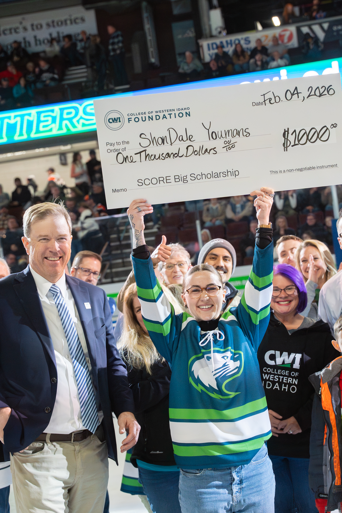 Student holding a large check in front of crowd