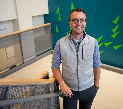 Cody Phelps stands in front of backdrop and near stair railing